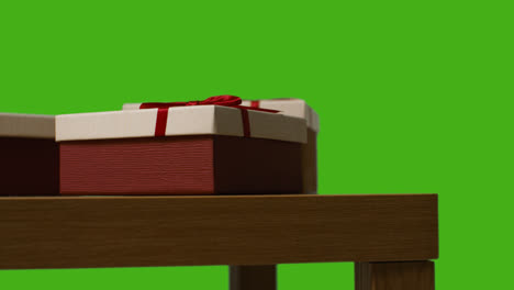 Close-Up-Of-Gift-Wrapped-Presents-On-Table-Shot-Against-Green-Screen